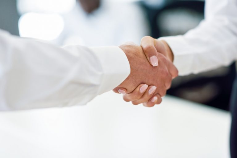 Caucasian businessman shaking hands with businesswoman in an off
